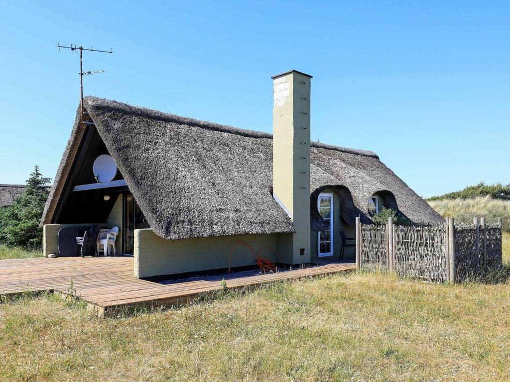 a house with a thatched roof and a wooden deck at Holiday Home Kræ in Klegod