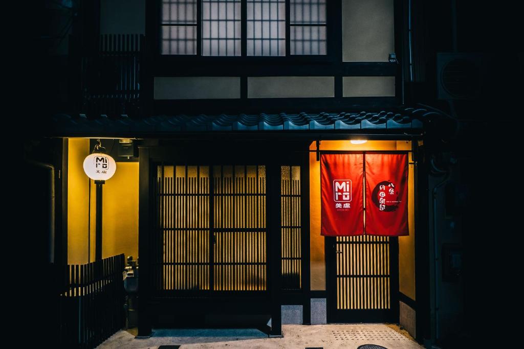- un bâtiment avec une porte rouge et un panneau. dans l'établissement Miro Hachijo Uchidacho Tei, à Kyoto