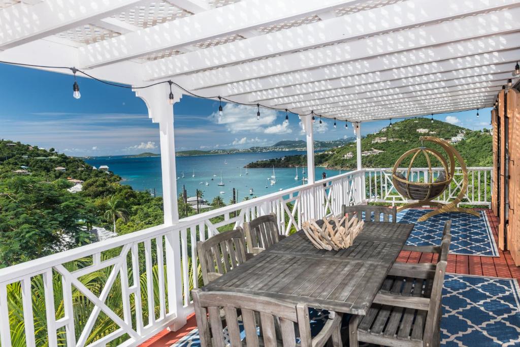 a wooden table on a balcony with a view of the ocean at Limetree Cottage at Chocolate Hole in Cruz Bay