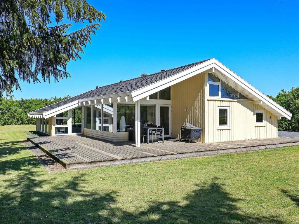 une petite maison avec une grande terrasse en bois dans l'établissement 10 person holiday home in Hj rring, à Lønstrup