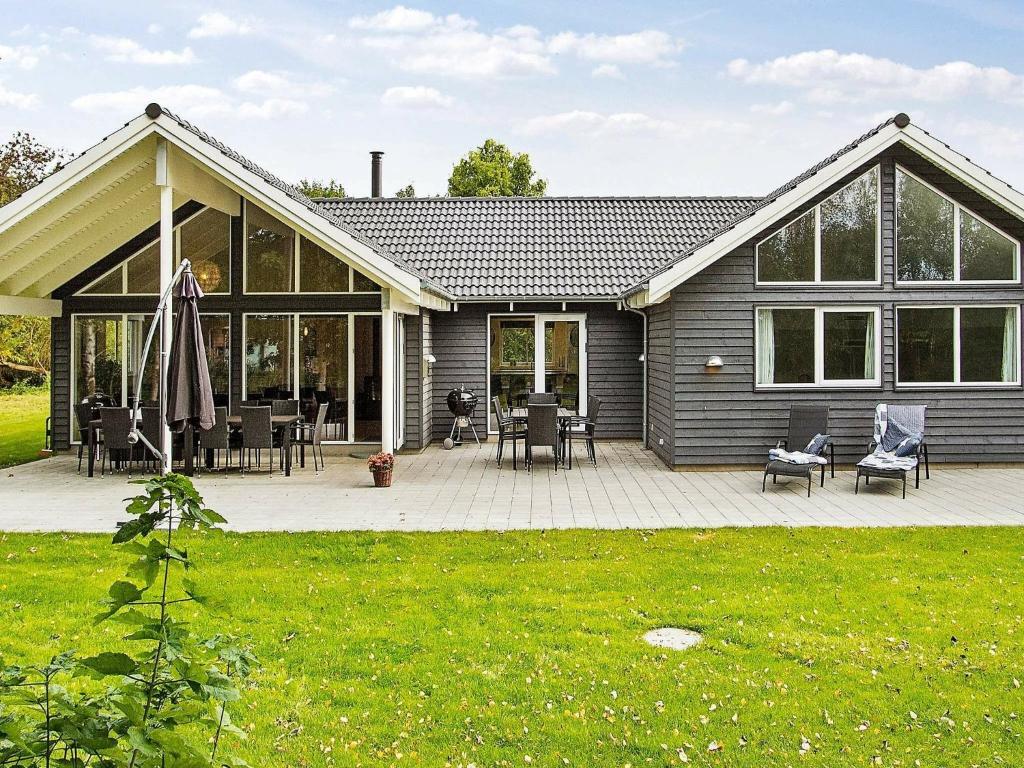 a house with a patio with chairs and tables at 18 person holiday home in H jby in Højby