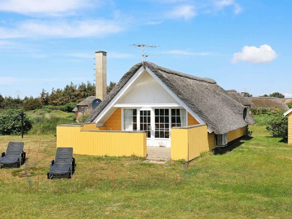 een klein huis met een rieten dak en 2 stoelen bij 6 person holiday home in Ringk bing in Ringkøbing