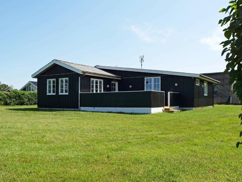 a black house with a green lawn in front of it at 8 person holiday home in Hemmet in Hemmet