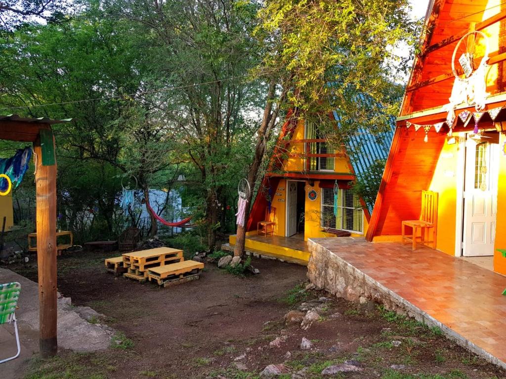 una vista exterior de una casa con mesa y bancos en Cabañas Pancho Segunda Usina en Embalse