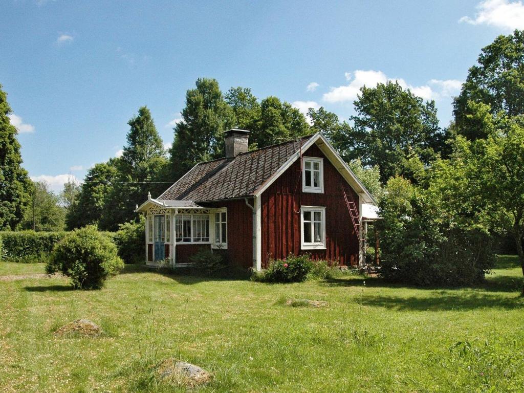 una pequeña casa roja en un campo de hierba en 5 person holiday home in KALVSVIK en Kalvsvik