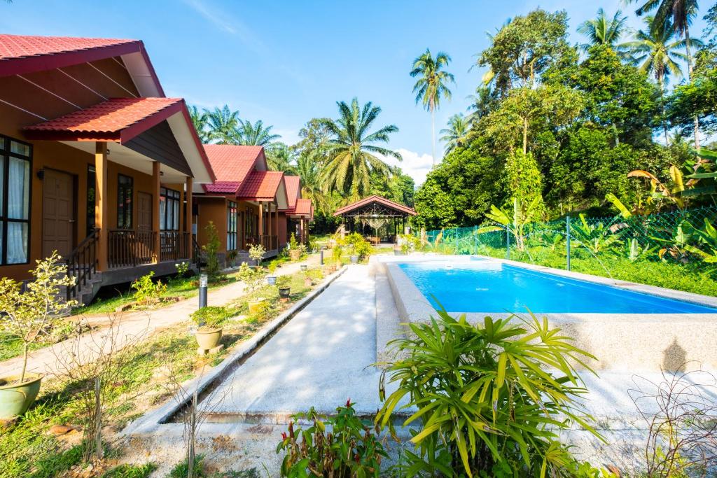 a villa with a swimming pool in front of a house at Cinta Abadi Resort in Bidur