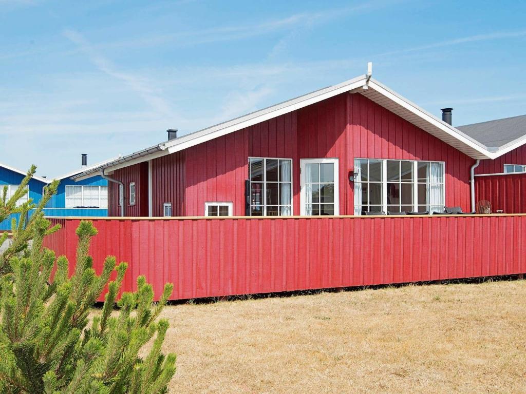 a red house with a red fence at 6 person holiday home in Hvide Sande in Hvide Sande