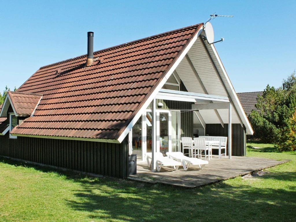 a house with a wooden deck with a roof at 6 person holiday home in R m in Toftum