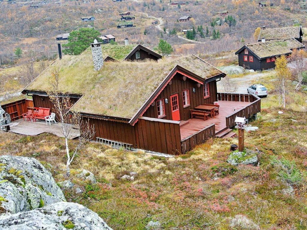 eine Blockhütte mit einem Grasdach auf einem Hügel in der Unterkunft 11 person holiday home in Edland in Vågsli
