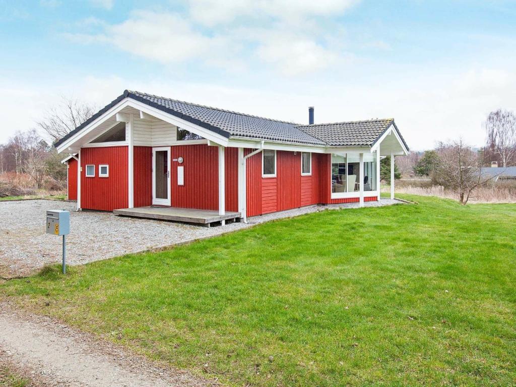 une maison rouge avec une pelouse verte devant elle dans l'établissement Holiday home Asnæs III, à Asnæs