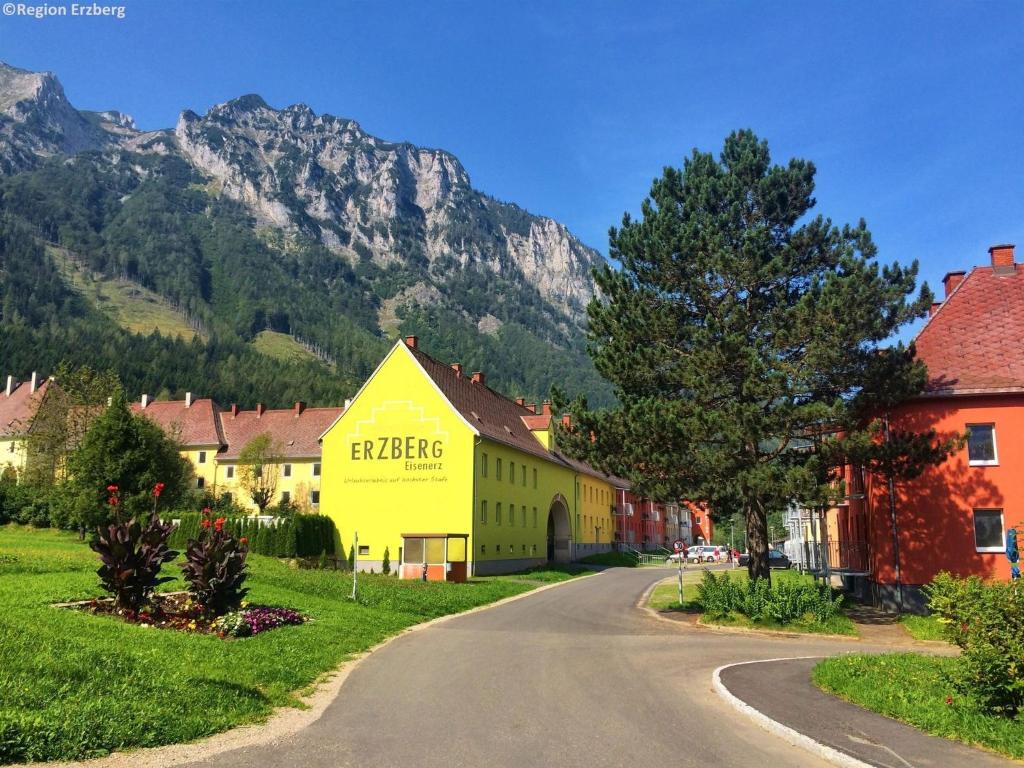 a yellow building on a street with mountains in the background at Cozy Apartment near Ski Area in Eisenerz in Eisenerz