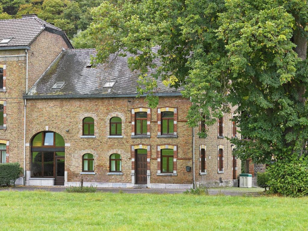 a brick building with green windows and a tree at A large family house in Stavelot