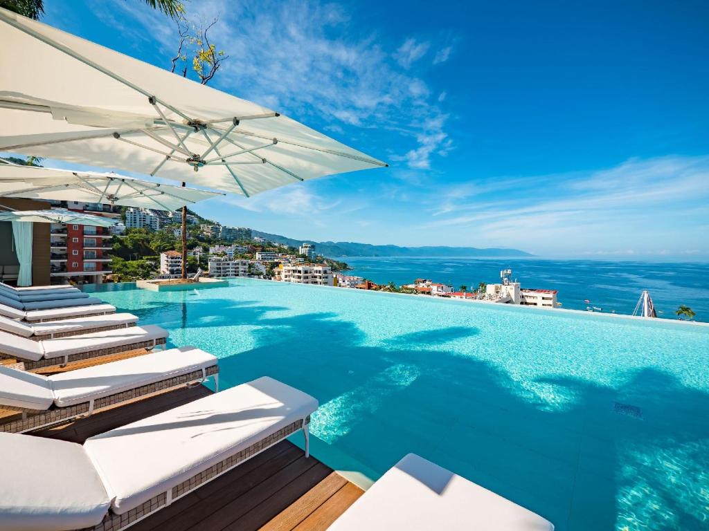 una piscina con sillas y sombrilla en PIER 57 - 509 Unique 2 BR Condo Romantic Zone, en Puerto Vallarta