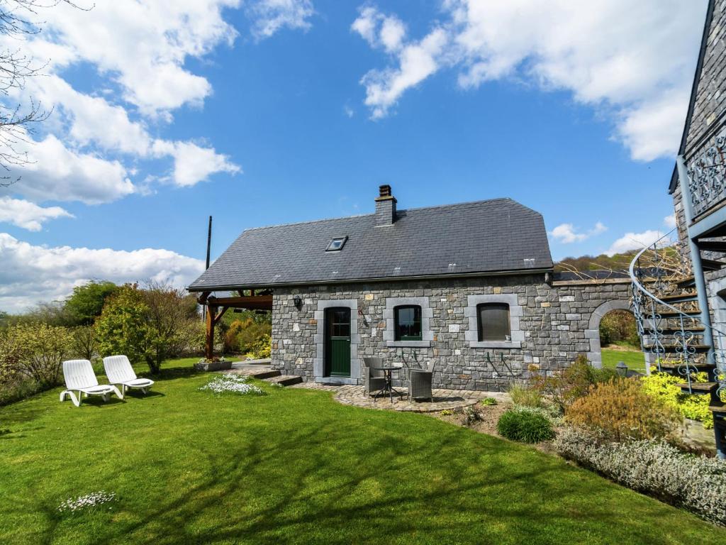 une maison en pierre avec 2 chaises blanches dans une cour dans l'établissement Charming cottage for 2pers and a baby in the Land of the Valley, à Roly