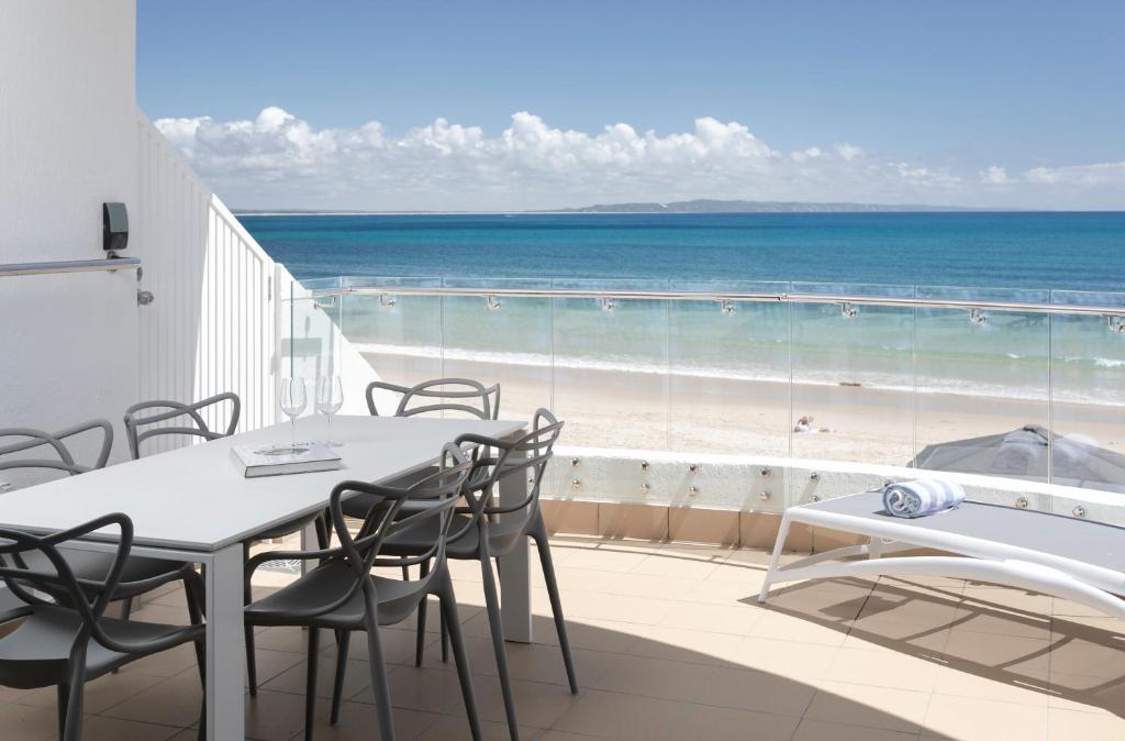 a balcony with a table and chairs and the beach at La Mer Apartment 8, Noosa Heads in Noosa Heads