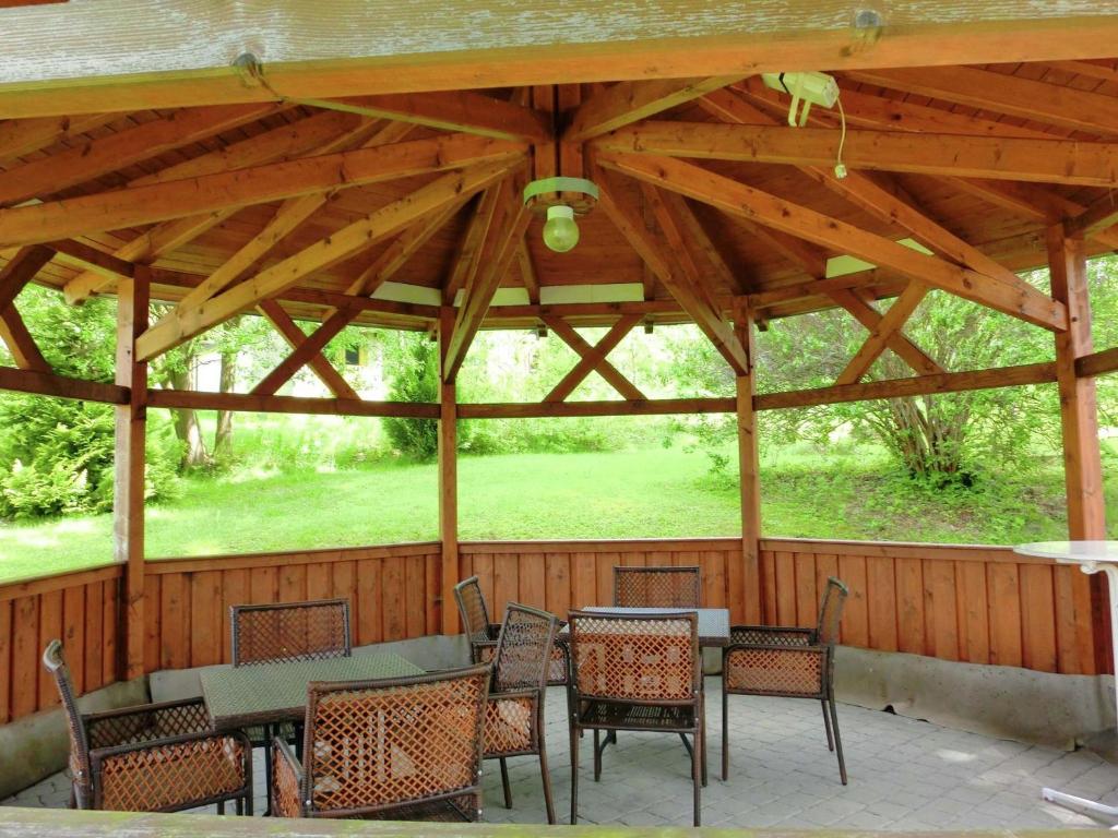 a wooden pavilion with tables and chairs on a patio at Apartment in a villa with garden in Borstendorf in Wünschendorf
