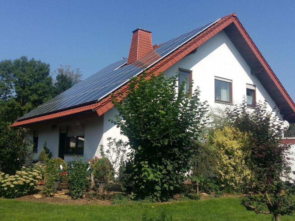 a white house with a metal roof and some bushes at Cozy Apartment in Merlsheim with Garden in Nieheim