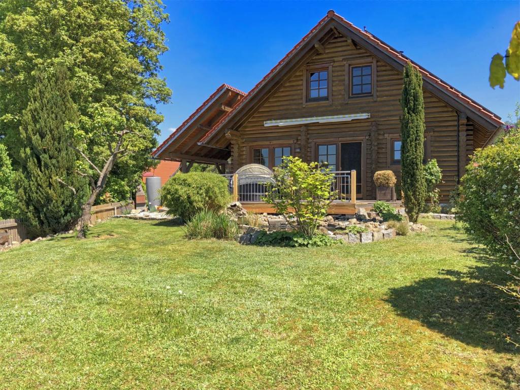 une maison en rondins avec une cour devant elle dans l'établissement Wooden holiday home with sauna, à Teunz