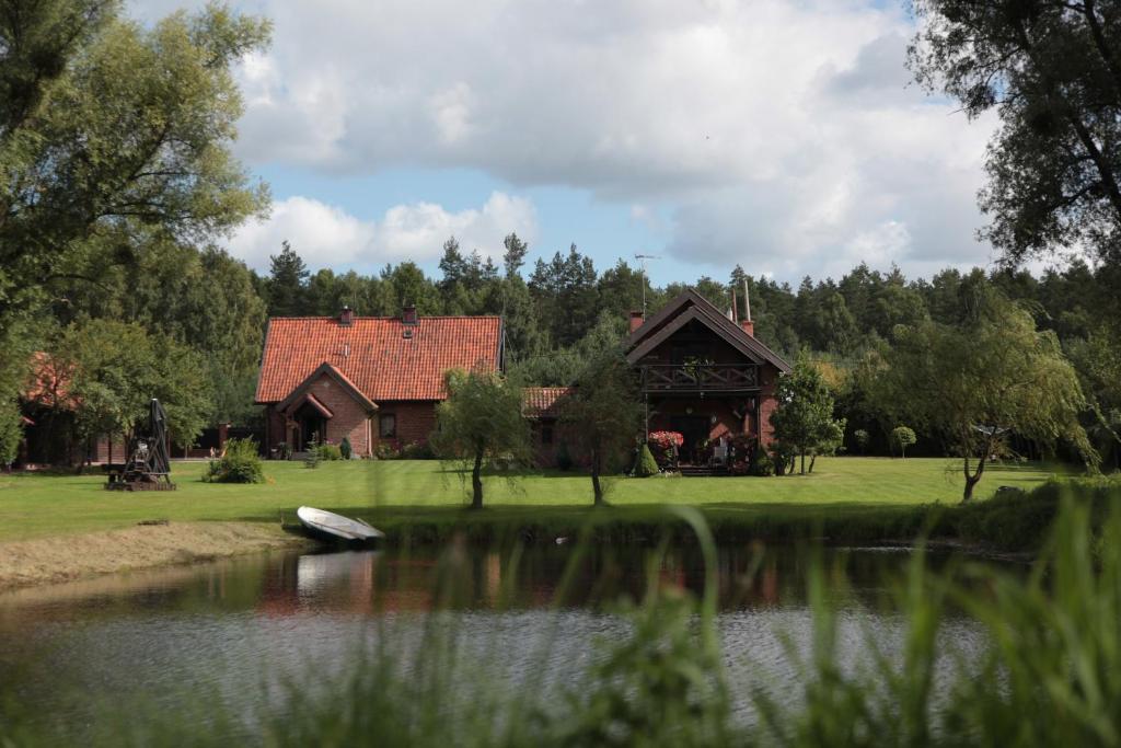 una casa con un lago delante de ella en Orlik Mazury, en Stare Jabłonki
