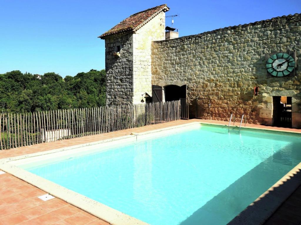 a swimming pool in front of a building with a clock at Cozy House in Lot with Pool and Terrace in Saint-Caprais-de-Lerm