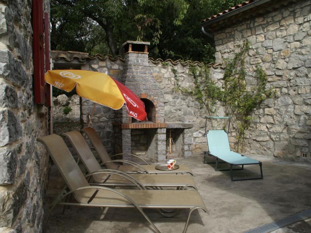 a group of chairs and an umbrella next to a stone fireplace at Holiday Home in a Nature Reserve in Beaulieu in Beaulieu