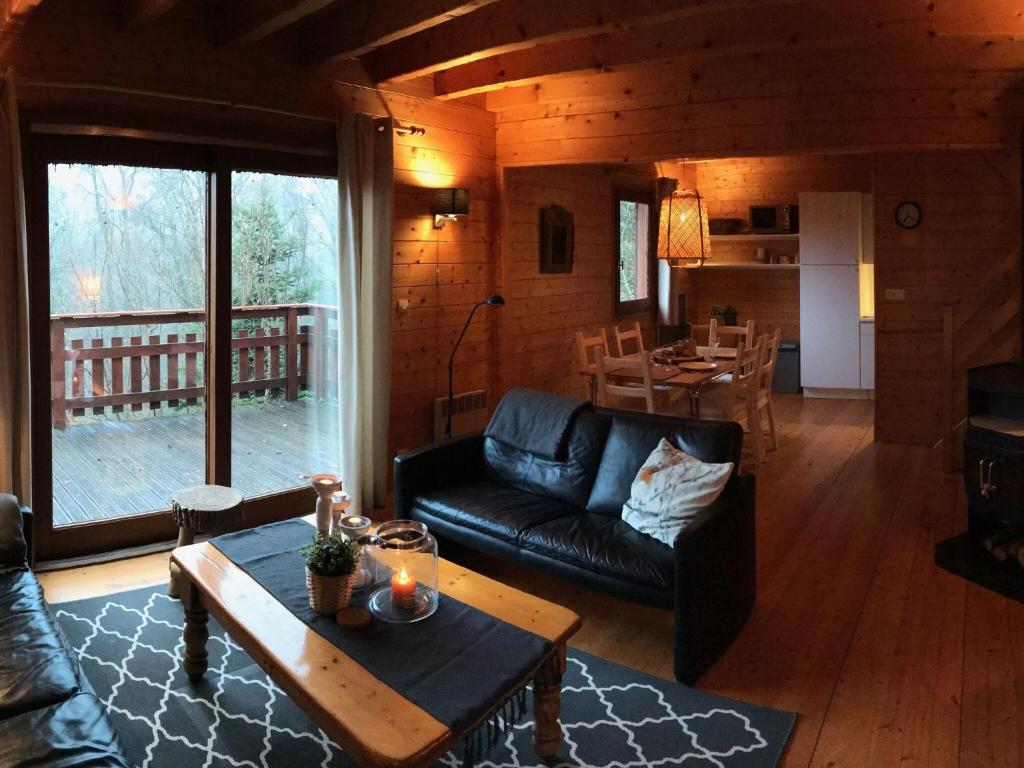 a living room with a black leather couch and a table at Pretty chalet in Beaulieu with private pool in Beaulieu