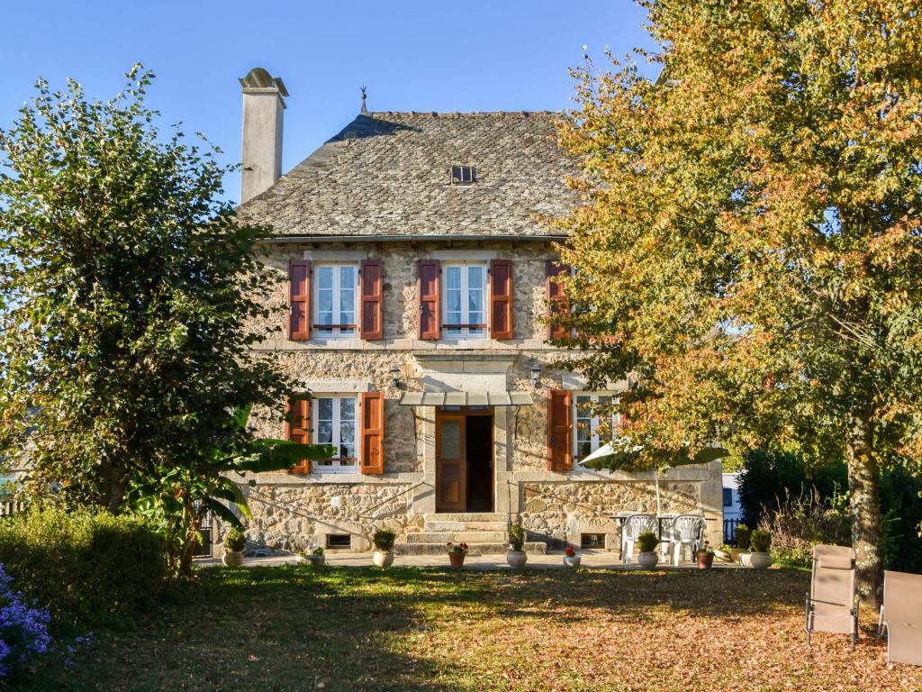 une ancienne maison en pierre avec des arbres devant elle dans l'établissement Comfortable holiday home with garden, à Cassaniouze