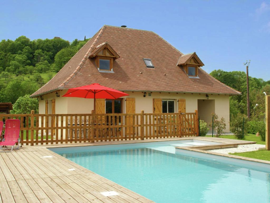 Modern holiday home with private pool في Loubressac: منزل مع مسبح ومظلة حمراء