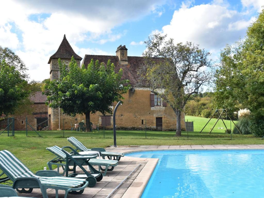 a swimming pool with chairs and a house in the background at Vintage Holiday Home in Besse with Swimming Pool in Saint-Pompont