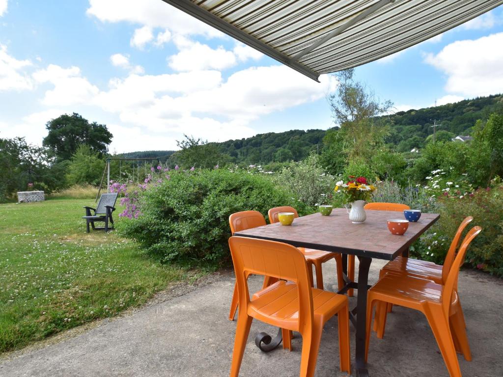 a wooden table with orange chairs sitting on a patio at Comfy holiday home in Crux La Ville with fenced garden in Crux-la-Ville
