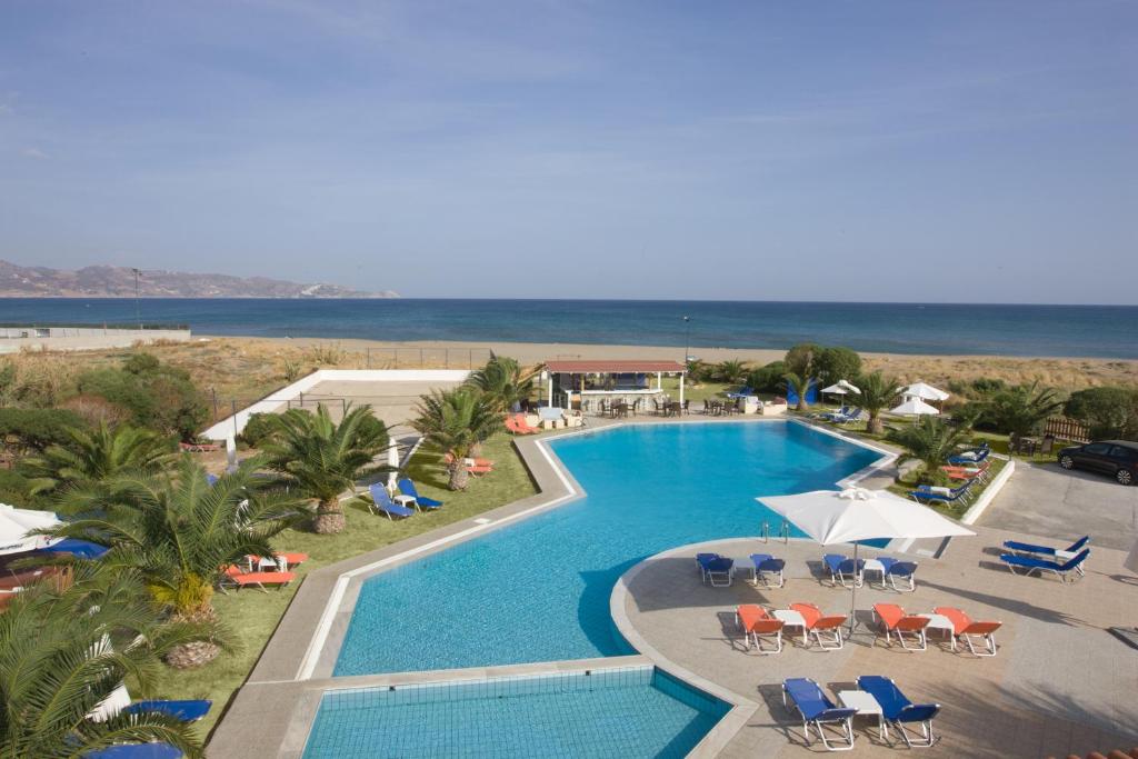 アムーダラ・イラクリオンにあるAkti Corali Hotelの海と椅子付きのスイミングプールの景色を見渡せます。