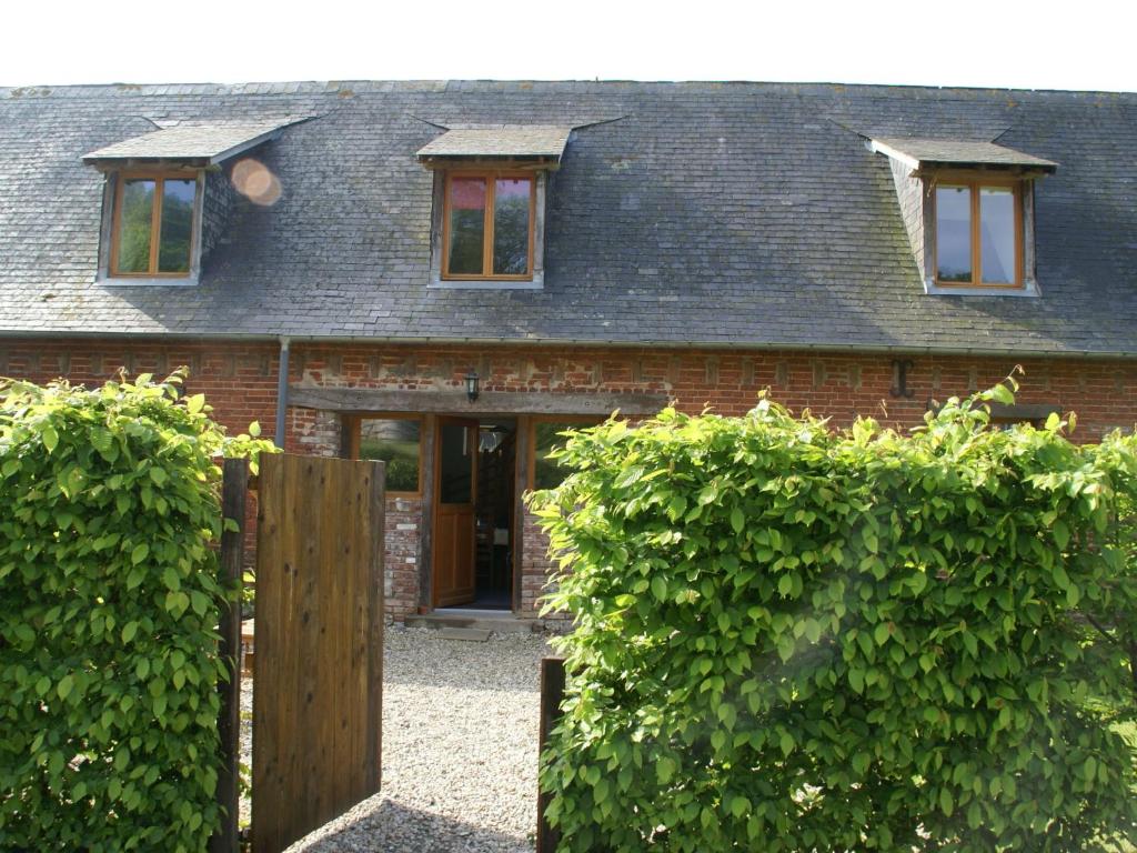 a brick house with a wooden fence in front of it at Classic Cottage in Le Bourg Dun with Garden in Le Bourg-Dun