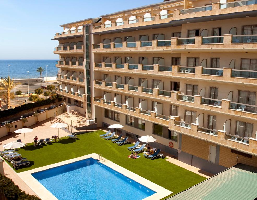 a hotel with a pool and the ocean in the background at BQ Andalucia Beach Hotel in Torre del Mar