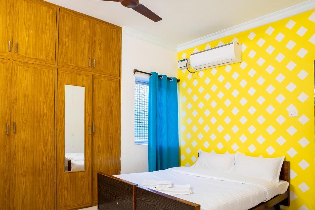 ein Schlafzimmer mit einem Bett und einer gelben Wand in der Unterkunft Fiji Villa in Puducherry