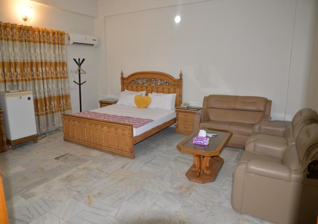 a bedroom with a bed and a couch and a table at Step inn Guest House Sukkur in Kalar Goth