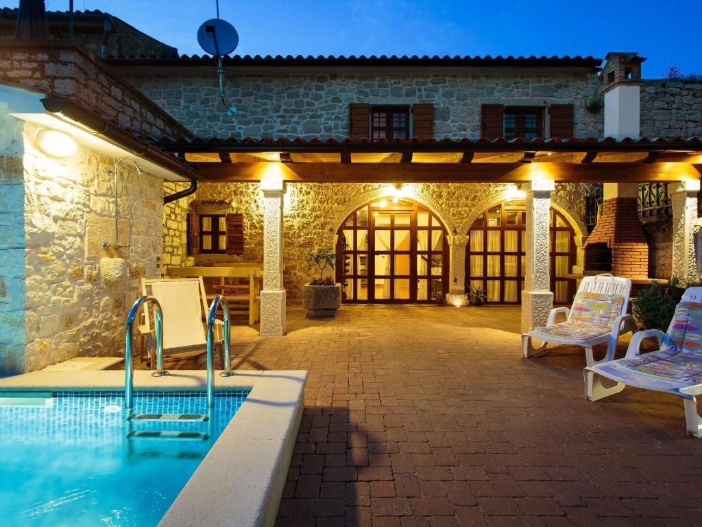 una piscina all'aperto con due sedie e un edificio di Cosy holiday home in Vrsar with private pool a Marasi