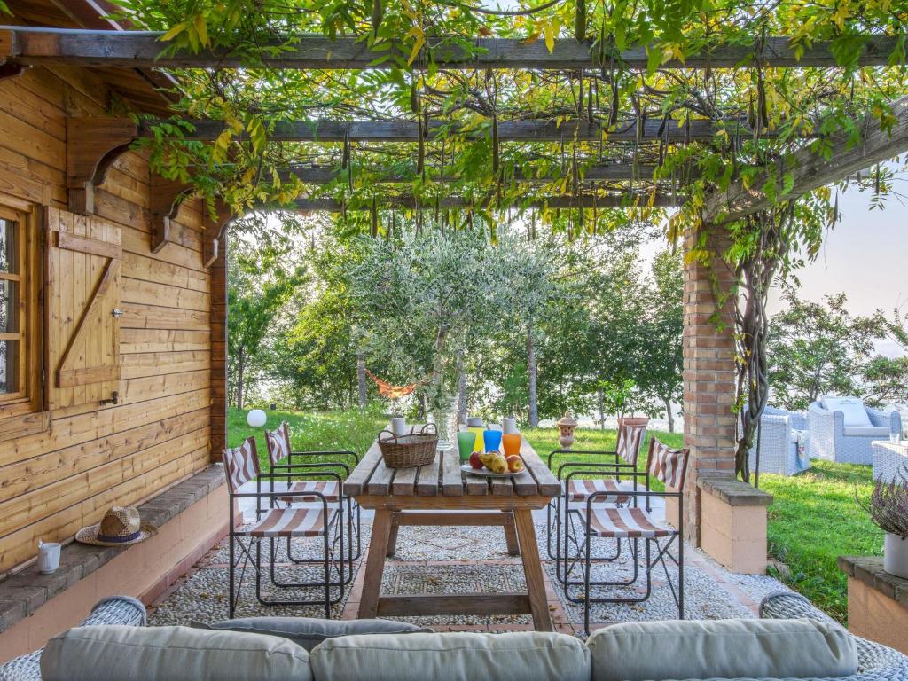 patio con tavolo e sedie sotto un pergolato di Belvilla by OYO Le Castorelle a Montemaggiore al Metauro