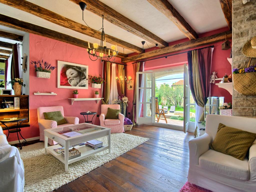 a living room with pink walls and wooden floors at Lush Villa with Artistic Interiors Pool in Baderna