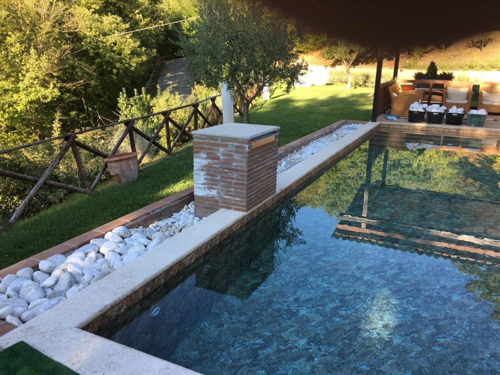 a swimming pool in a yard with rocks in the water at Belvilla by OYO Villa Valtopina in Valtopina