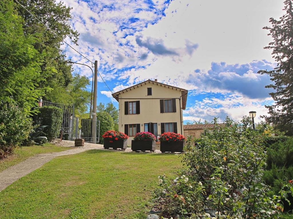 a small house with two flower pots in front of it at Flat with swimming pool garden BBQ and parking in Arcevia