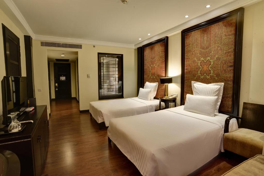 Habitación de hotel con 2 camas y sofá en Pearl Continental Hotel, Muzaffarabad, en Muzaffarabad