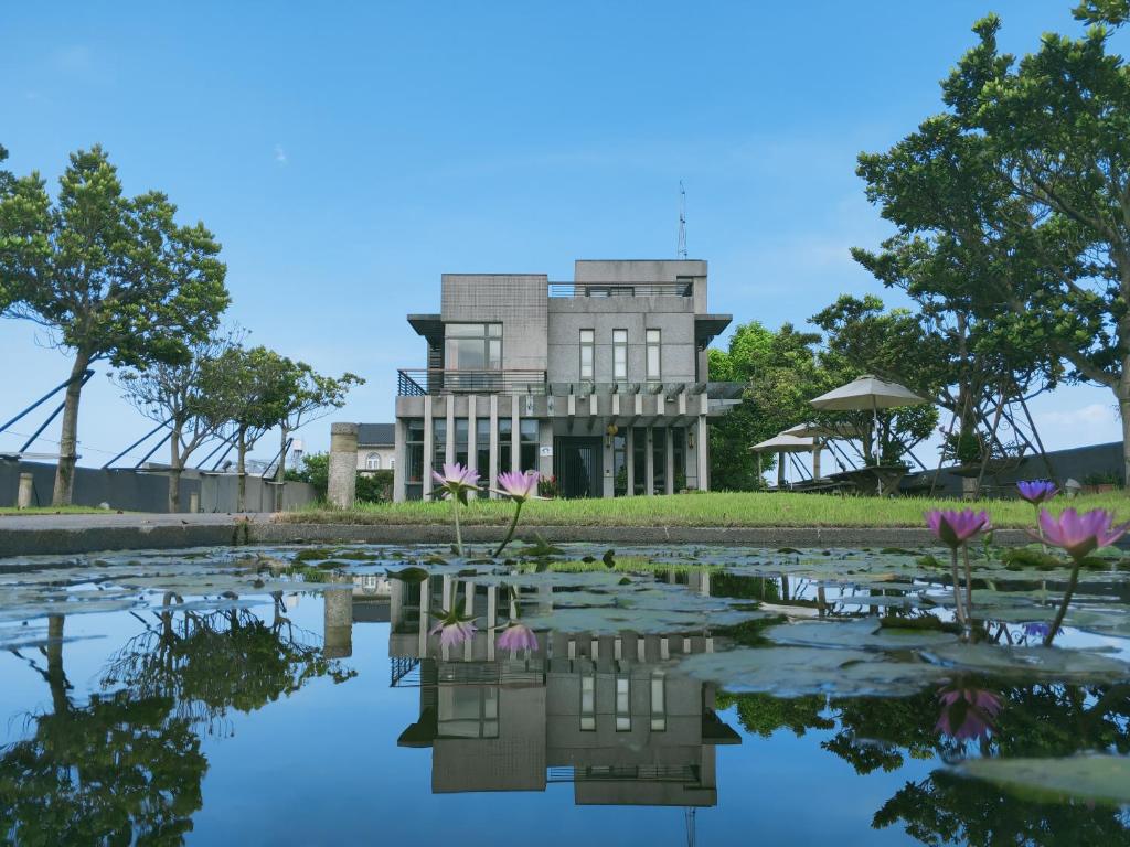 a house behind a pond with flowers in front of it at The Designer's House in Wujie