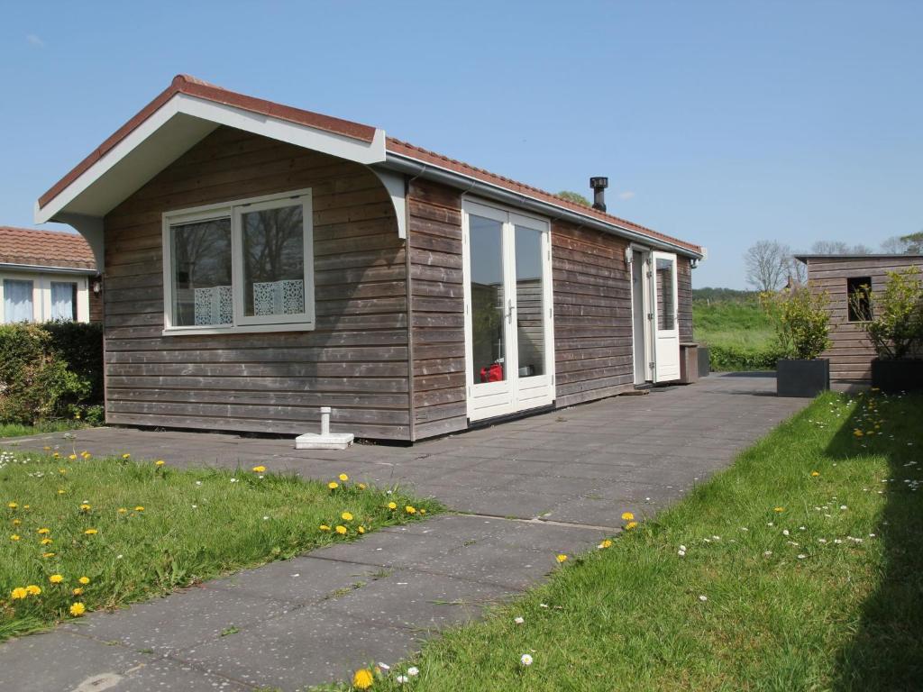 una pequeña casa con una entrada delante de ella en Comfortable bungalow near the beach, en Warmenhuizen