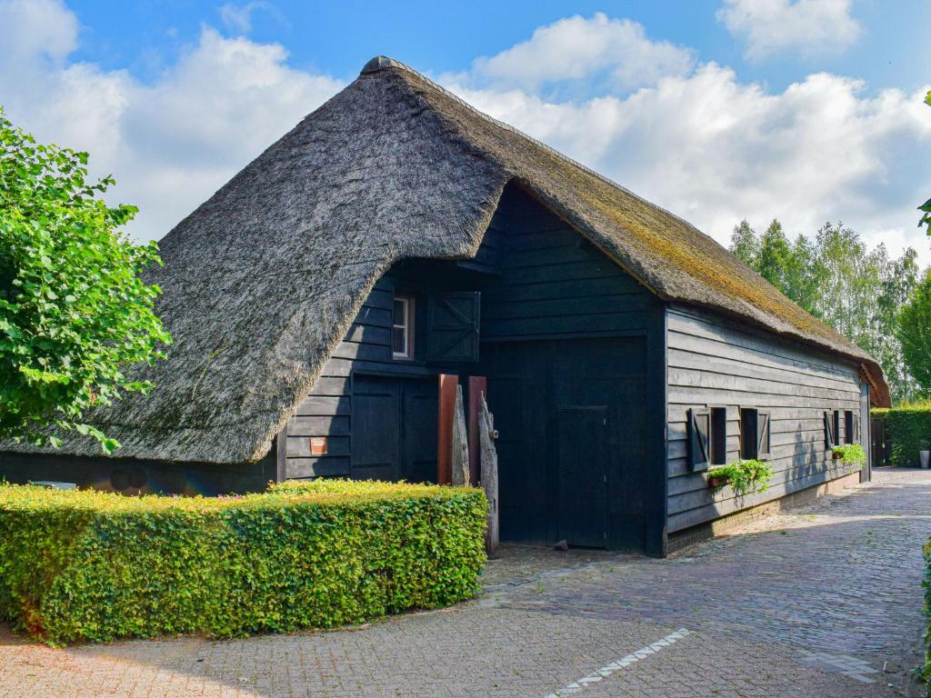 an old black and white barn with a thatched roof at Unique holiday home with a hot tub in Alphen