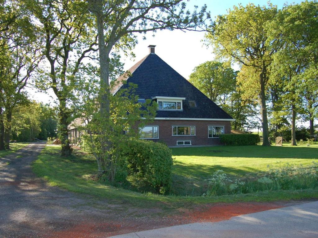 a brick house with a gambrel roof on a green yard at Rural holiday home with a lovely sunny terrace in Workum