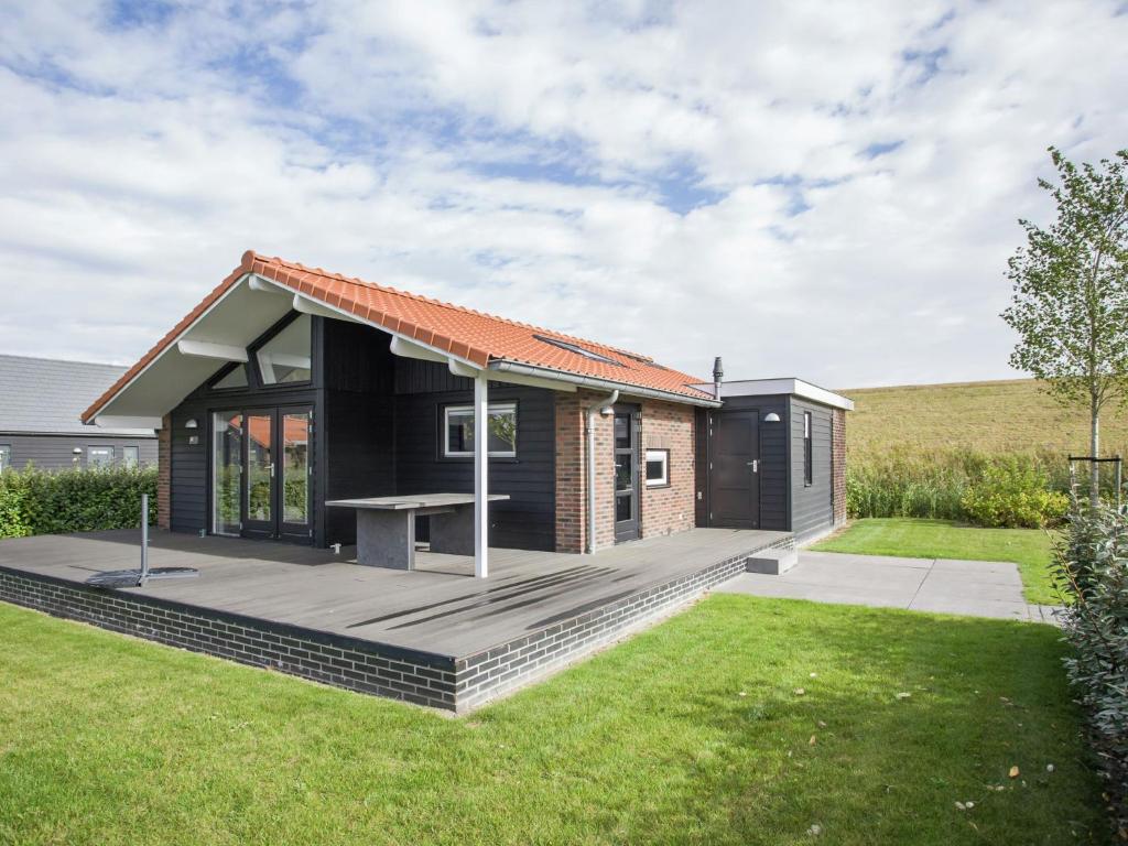 KattendijkeにあるHoliday Home in Kattendijke with Terraceの木製デッキ付きの小さな黒い家