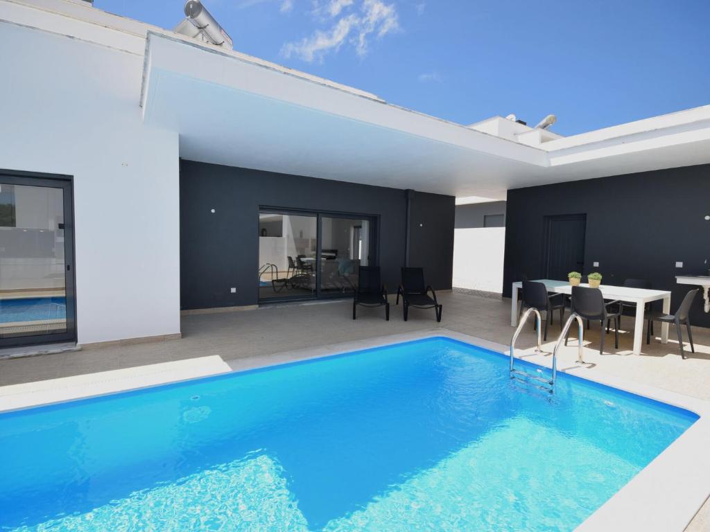 a house with a swimming pool and a dining room at Modern villa with private pool near the beautiful beach of Foz de Arelho in Nadadouro
