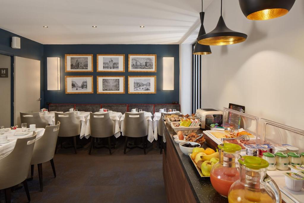 a dining room with tables and chairs with food at Hôtel Harvey in Paris