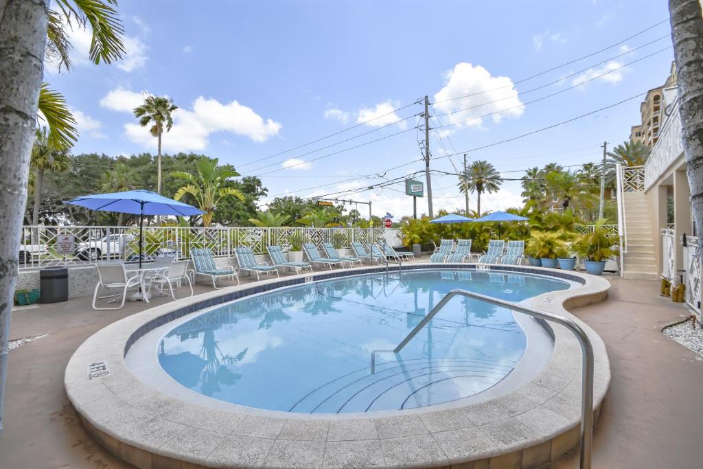 einen Pool mit Stühlen und einem Sonnenschirm in der Unterkunft Clearwater Beach Suites 105 condo in Clearwater Beach