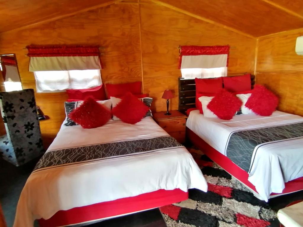 a bedroom with two beds with red pillows at The Guesthouse in Vanderbijlpark